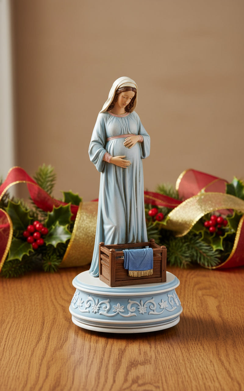 Statue of pregnant Mary in a blue dress with a wooden cradle on a white background